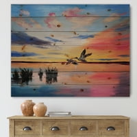 עיצוב אמנות 'ציפורי מנוף עפות במהלך שקיעה צבעונית' הדפס ימי וחופי על עץ אורן טבעי